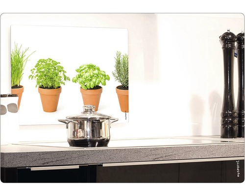 Kuchynská scéna s hrncom na sporáku a obrázkom byliniek ako ochranou proti striekajúcej vode