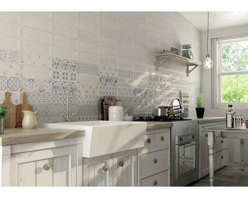 Svetlá kuchyňa s obkladanou stenou v bielej farbe a modrými vzormi, umývadlom a drevenou pracovnou doskou