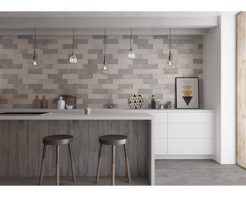 Moderná kuchyňa so sivými obkladovými tehlami, barovým pultom s barovými stoličkami a bielymi skrinkami.