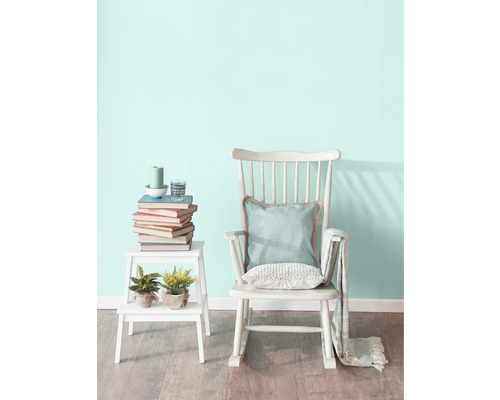 Scéna s hojdacím kreslom, odkladacím stolíkom, knihami a dekoráciami v svetlej miestnosti.