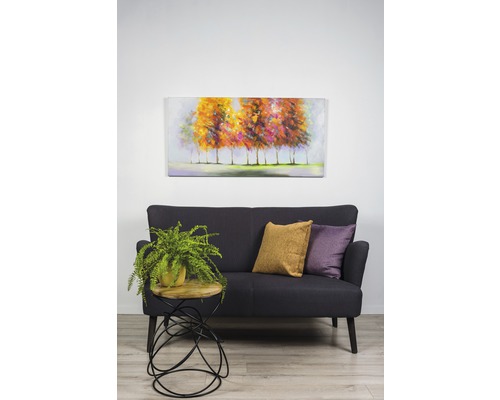 Scéna s pohovkou, vankúšmi, príručným stolíkom s rastlinou a nástennou maľbou.