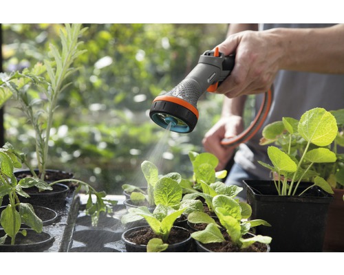 Zavlažovanie záhrady záhradnou striekacou pištoľou pre sadenice v kvetináčoch.