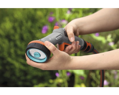 Osoba drží v ruke zavlažovací postrekovač Gardena s niekoľkými prúdmi.