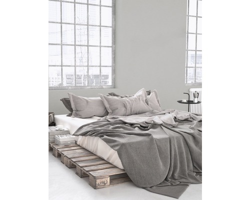 Spálňa s rámom postele z drevených paliet, posteľnou bielizňou a vankúšmi