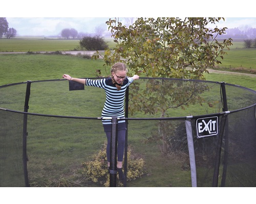 Dievča balansuje na záhradnej trampolíne so sieťou. Logo EXIT.