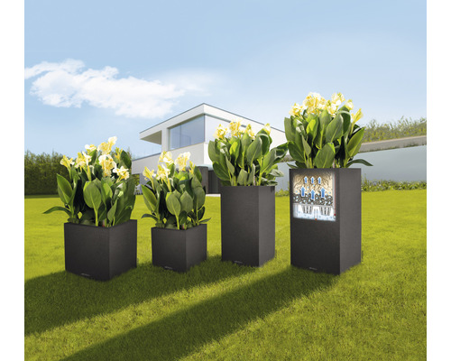 Štyri hranaté kvetináče s rastlinami rôznych veľkostí v záhrade