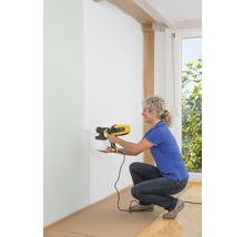 Žena používa striekací systém na farby na vnútorné steny.