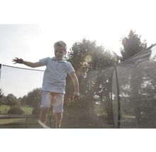 Dieťa skáče na záhradnej trampolíne s bezpečnostnou sieťou.