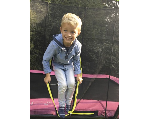 Chlapec lezie na záhradnú trampolínu s bezpečnostnou sieťou