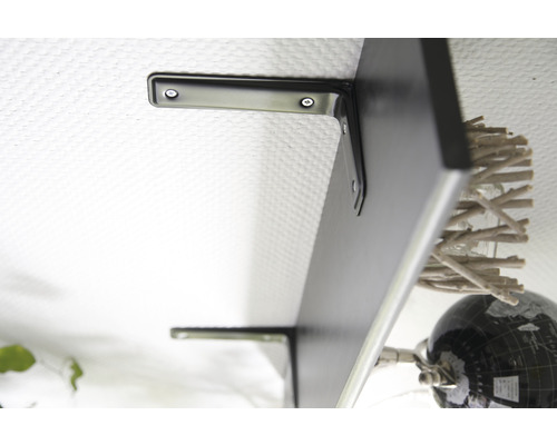 Čierna nástenná polica s držiakmi na bielej stene