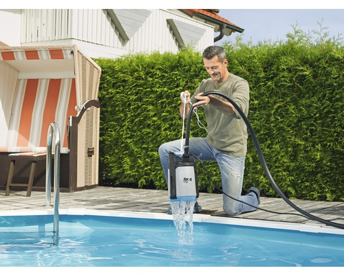 Muž používa ponorné čerpadlo pri bazéne na vypúšťanie vody.