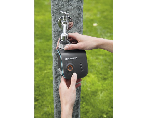Osoba pripevňuje zavlažovací počítač Gardena Smart Water Control na vonkajší vodovodný kohútik.