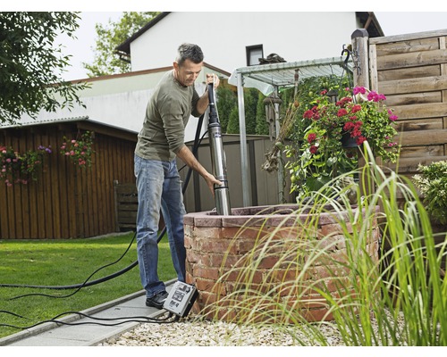 Muž inštaluje hlbinné čerpadlo do záhradnej studne.