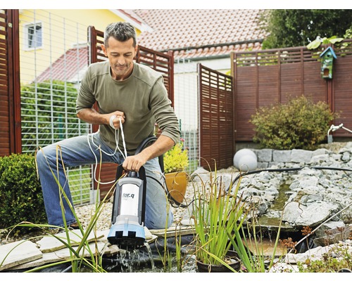 Muž obsluhuje jazierkové čerpadlo značky for.q v záhradnom jazierku.