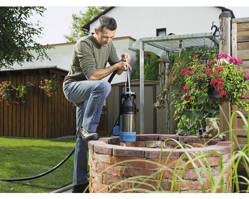 Muž obsluhuje hlbinné čerpadlo na studni v záhrade.