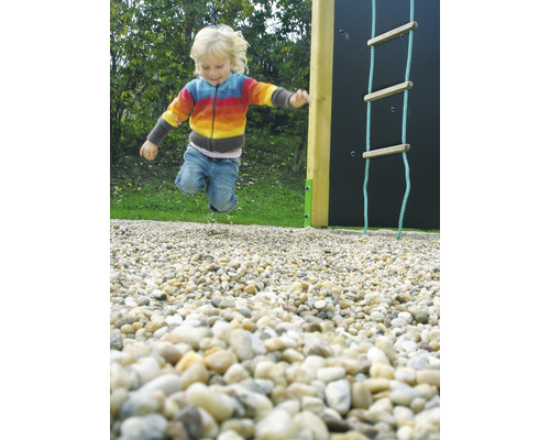 Dieťa skáče na ihrisku vedľa lezeckej steny a povrazového rebríka.