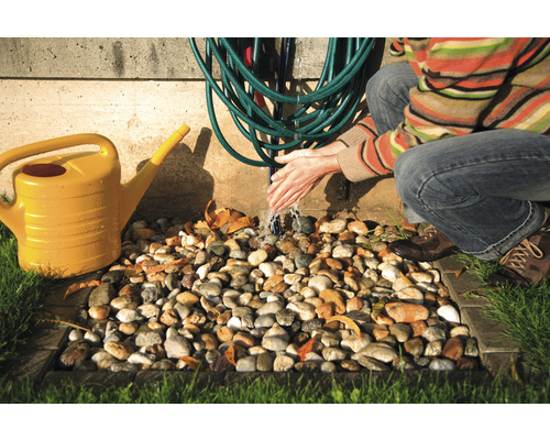 Záhradná zavlažovacia scéna so žltou kanvou, záhradnou hadicou a osobou, ktorá si umýva ruky