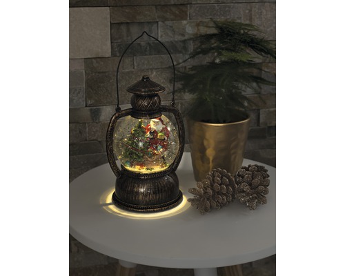 Dekoratívna snehová guľa lampáš s vianočným motívom a osvetlením.