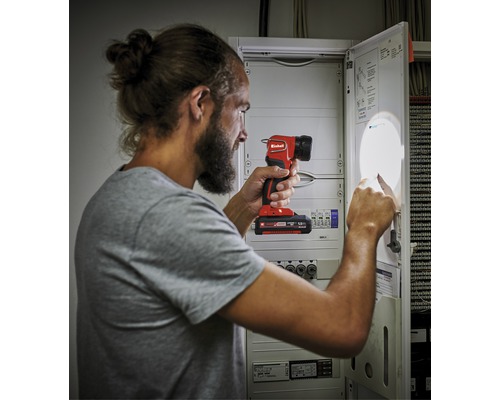 Muž osvetľuje poistkovú skrinku akumulátorovou lampou.