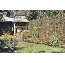 Scéna so záhradnou studňou, prúteným plotom, kvetinovým vozíkom a osadenými prútenými debničkami