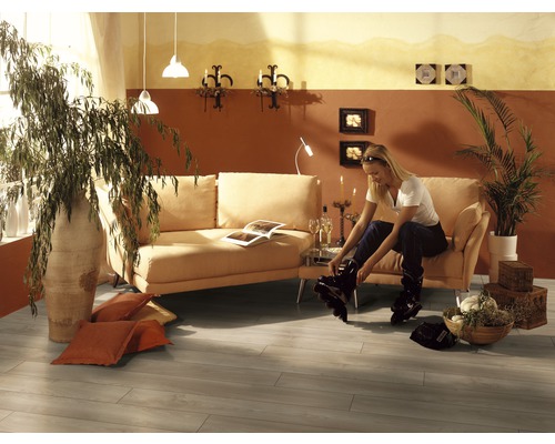 Obývacia izba s pohovkou, izbovými rastlinami a ženou obúvajúcou si inline korčule