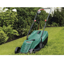Elektrická kosačka na trávu na trávniku pred kríkmi