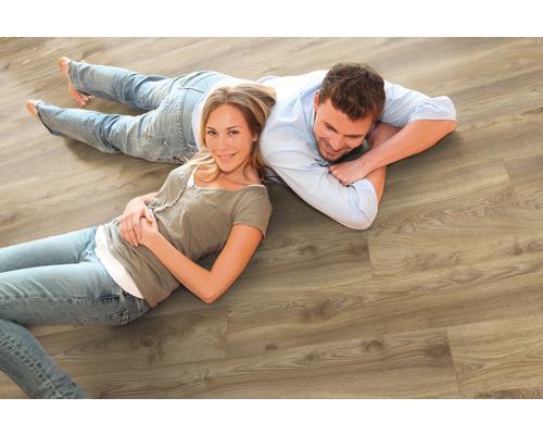 Pár leží na svetlej drevenej laminátovej podlahe.