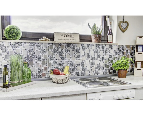 Detail modernej kuchyne s mozaikovými obkladmi ako zástenou, sporákom a rôznymi dekoráciami.