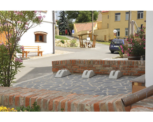 Vonkajší záber s tromi betónovými stojanmi na bicykle pred tehlovou stenou