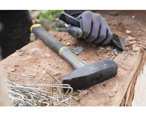 Kladivo, sekáč a pracovné rukavice ležia na stene.