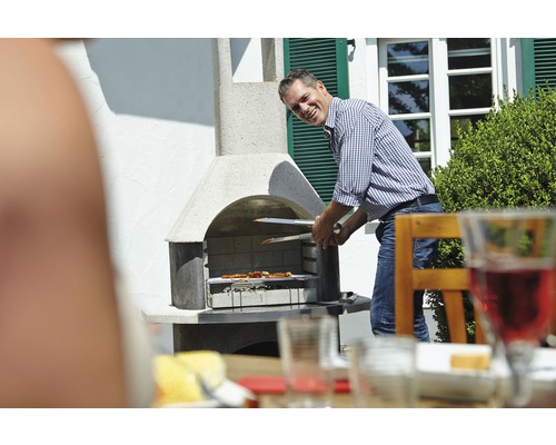 Muž griluje mäso grilovacími kliešťami na záhradnom grile.