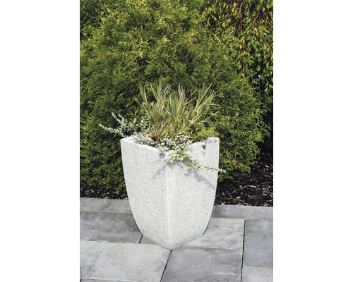 Kamenný kvetináč s rastlinami v záhrade