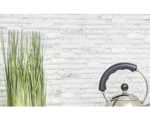 Dekoratívna umelá rastlina a čajová kanvica pred stenou z mozaikových dlaždíc