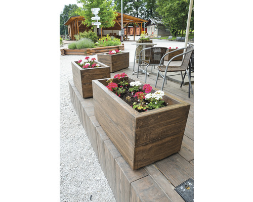 Tri osadené obdĺžnikové drevené kvetináče v exteriéri.