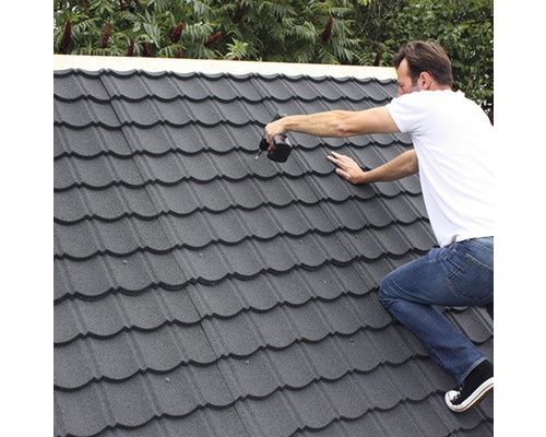 Remeselník montuje kovové strešné tašky pomocou akumulátorového skrutkovača