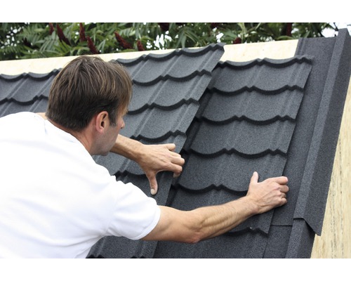 Muž kladie strešné tašky na strechu