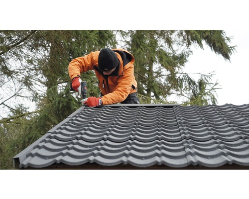 Remeselník montuje strešné tašky pomocou akumulátorového skrutkovača