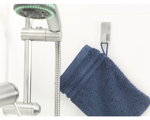 Sprchová tyč s ručnou sprchou a modrý uterák na háku