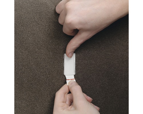 Osoba pripevňuje lepiaci háčik na stenu.