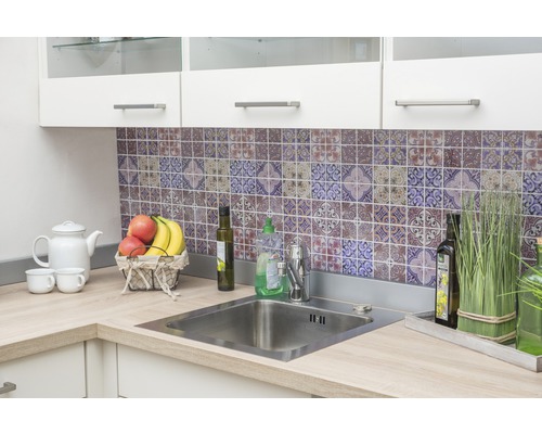 Kuchynský drez s batériou a pracovnou doskou pred stenou so vzorovanými dlaždicami