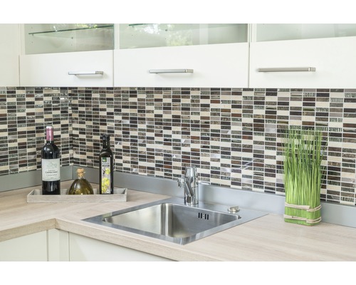 Kuchynský drez s batériou, mozaikové obklady a dekorácie na pracovnej doske.