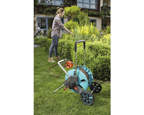 Žena používa záhradný hadicový vozík Gardena v záhrade