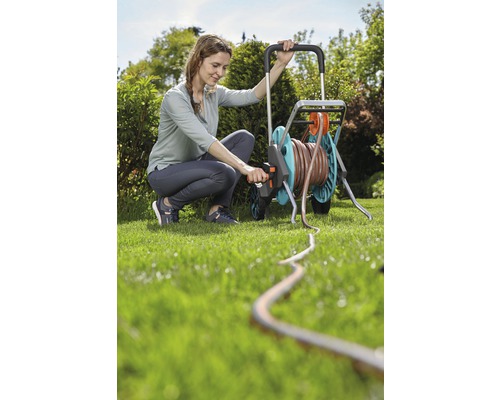 Žena obsluhuje vozík na hadicu v záhrade so záhradnou hadicou