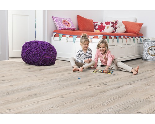 Detská izba so svetlohnedou drevenou podlahou, lavicou, vankúšmi, hračkami a dvoma hrajúcimi sa dievčatami