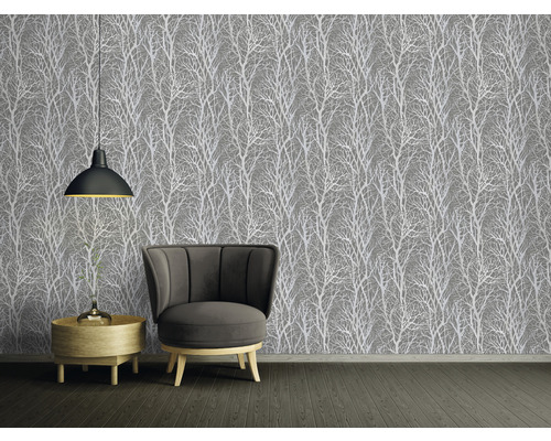 Pohľad na izbu so sivou tapetou so vzorom stromu, kreslom a odkladacím stolíkom