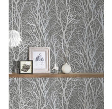 Scéna so sivou tapetou so vzorom stromu a policou s dekoráciami.