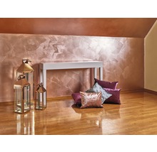 Interiér s dekoratívnou nástennou dekoráciou, biely konzolový stolík, ozdobné vankúše a kovové lampáše na drevenej podlahe