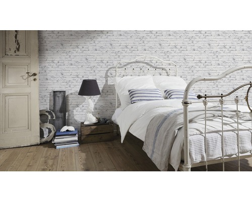 Svetlá spálňa s posteľou pred tapetou s tehlovou stenou