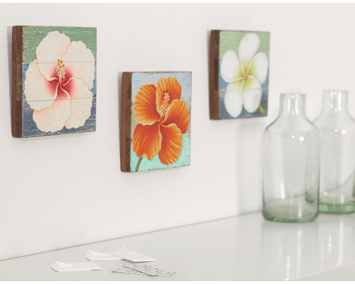 Dekoratívne nástenné obrazy s kvetinovými motívmi a sklenené fľaše na stole