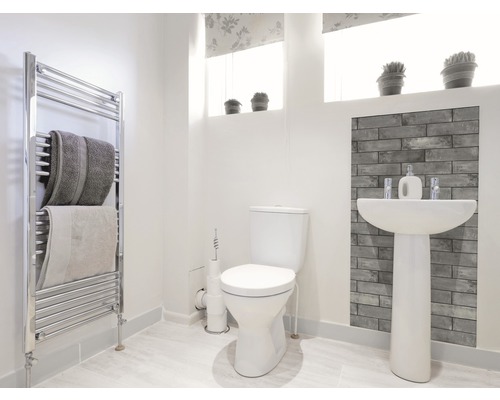 Svetlá kúpeľňa s toaletou, umývadlom, radiátorom a uterákmi.